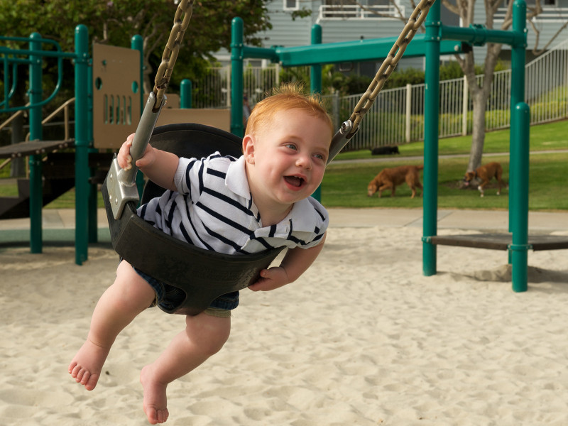 Devon happily flying around on a swingset at the playground in Encinitas, California, USA