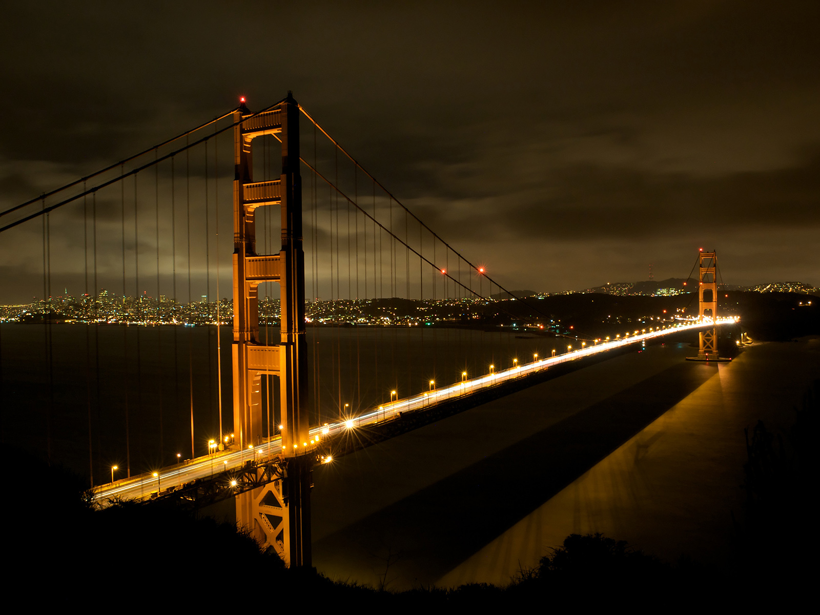 night shot of the Golden Gate Bridge with car lights streaking by in San Francisco, California, USA